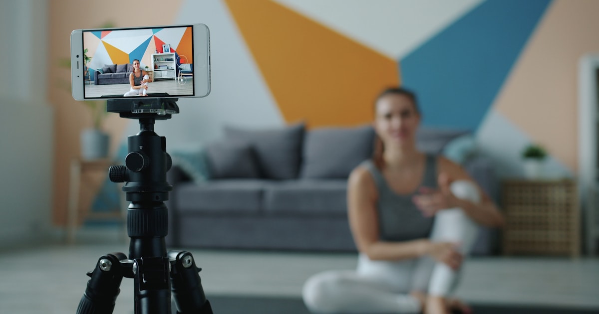 Kvinne filmer en vertikal video av seg selv med en smarttelefon montert på et stativ