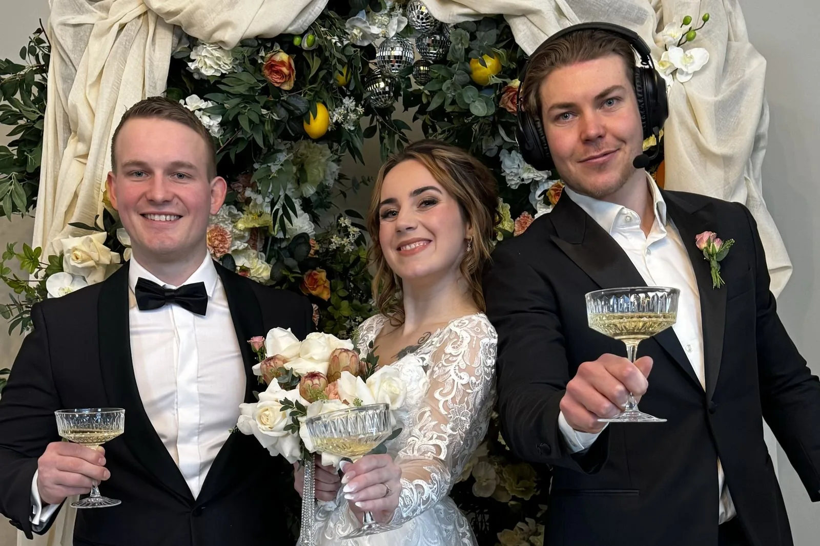 Oskar med headset skåler med et brudepar