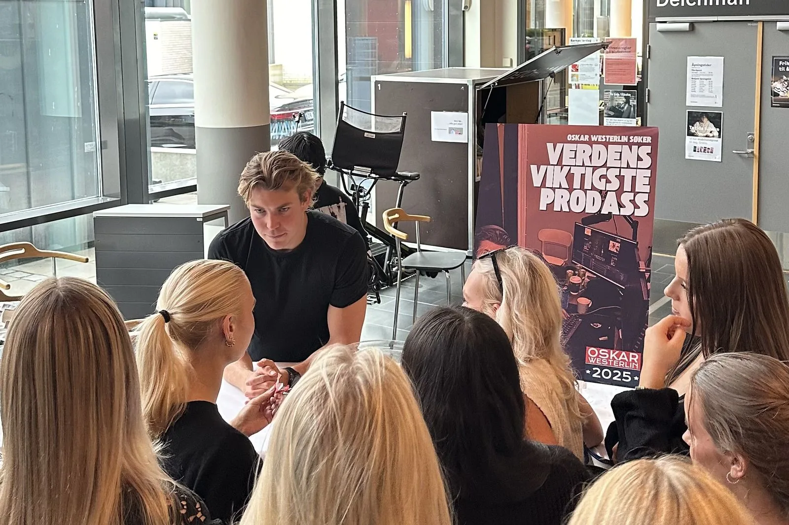 Oskar møter unge søkere, ved siden av en plakat for programmet